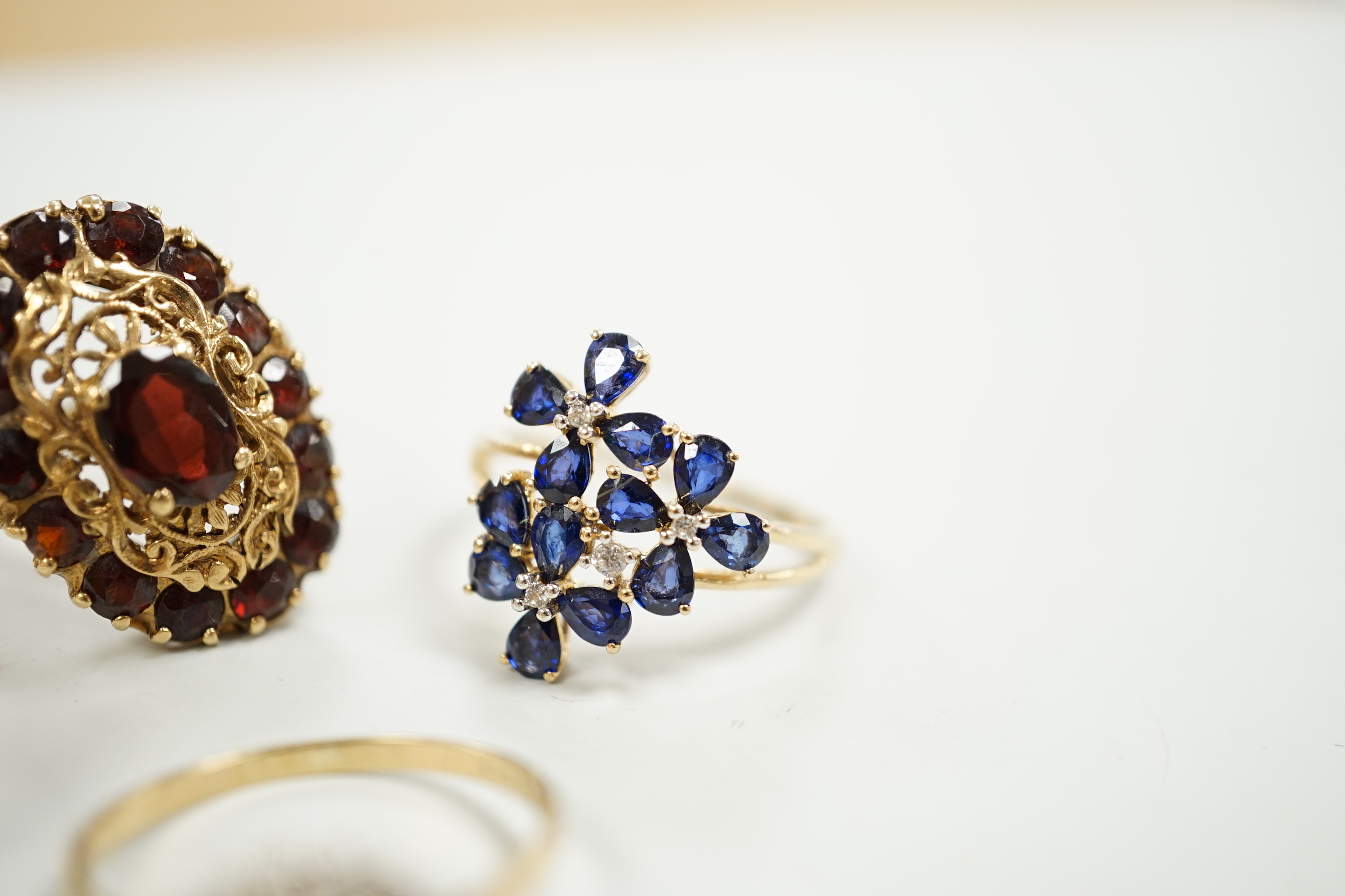 Four assorted modern 9ct gold and gem set dress rings including diamond cluster and garnet cluster, gross weight 13.6 grams.